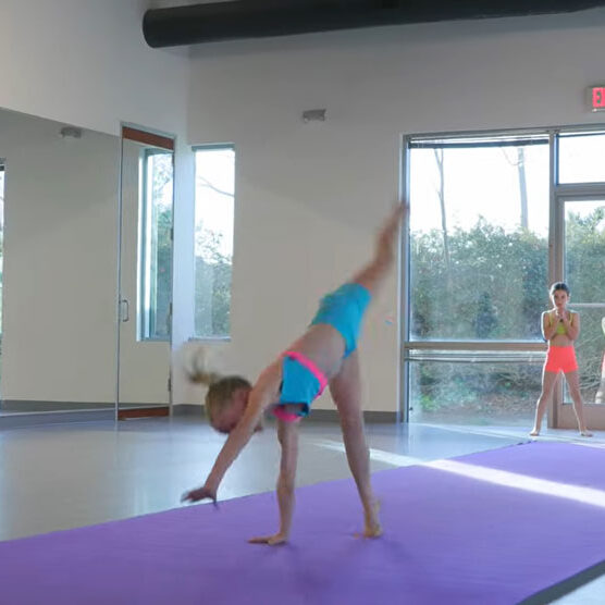 Young girl doing a somersault across mat