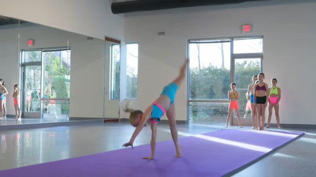 Young girl doing a somersault across mat