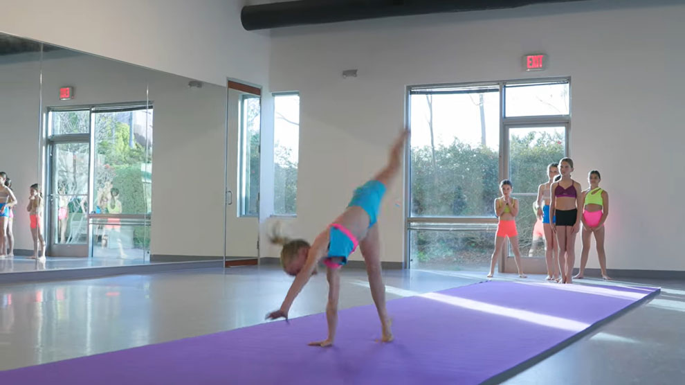 Young girl doing a somersault across mat